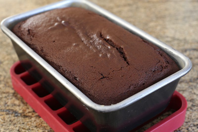 Baked moist chocolate loaf cake in the pan, cooling on a rack.