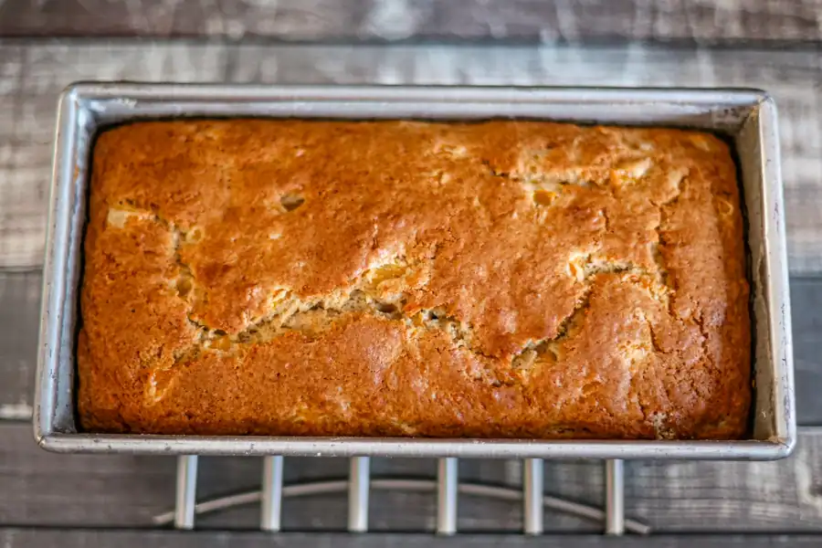 Warm baked peach quick bread on a cooling rack.