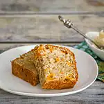 Moist banana bread with orange zest pieces on a white plate.