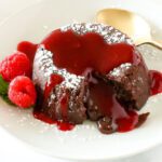 chocolate molten lava cake on a plate with raspberries and mint