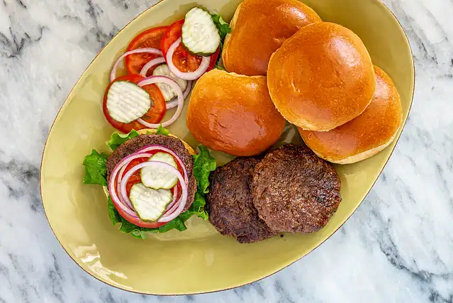 Assembling burgers with buns, lettuce, and fixings.