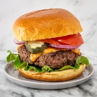Succulent beef burger with fresh vegetables and melted cheese on toasted bun.