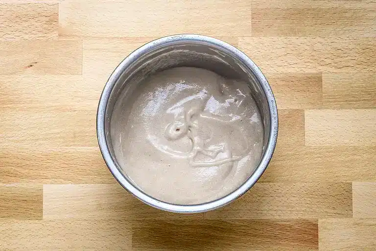 Creamy beige sauce in a round metal container.