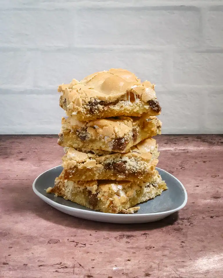Rich, gooey chocolate chip blondie bars stacked on a small plate.