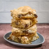 Butterscotch cookie bars stacked on a small plate with a rustic background.