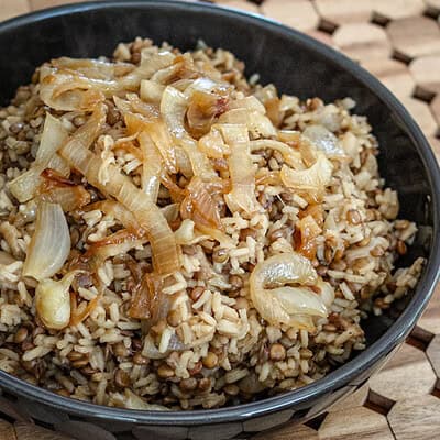 serving dish of mujadara with sautéed onion garnish