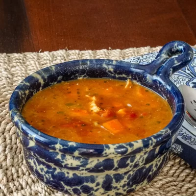 Warm bowl of vegetable soup in a decorative blue and white ceramic dish.