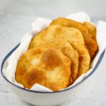 Native American fry bread is stacked in a bowl with paper towels.