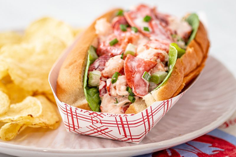 Closeup of a lobster roll with chips in a traditional New England hot dog roll.