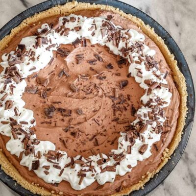 Creamy chocolate mousse pie topped with whipped cream and chocolate shavings.