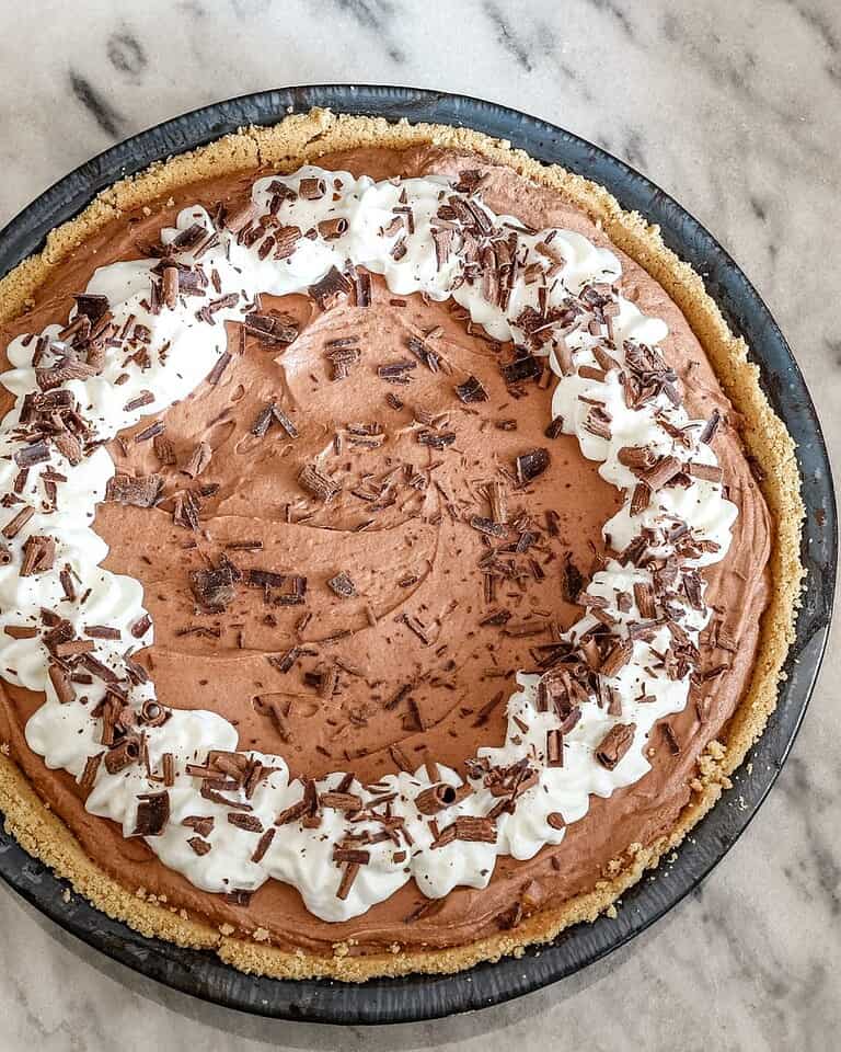 Creamy chocolate mousse pie topped with whipped cream and chocolate shavings.