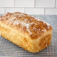 Freshly baked bread loaf cooling on a wire rack.