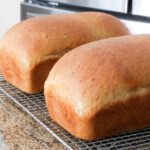 Two loves of oatmeal bread on a cooling rack.