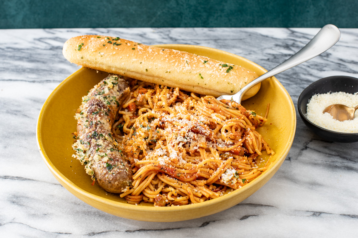 A serving of one pot spaghetti and sausages with a crispy topping.