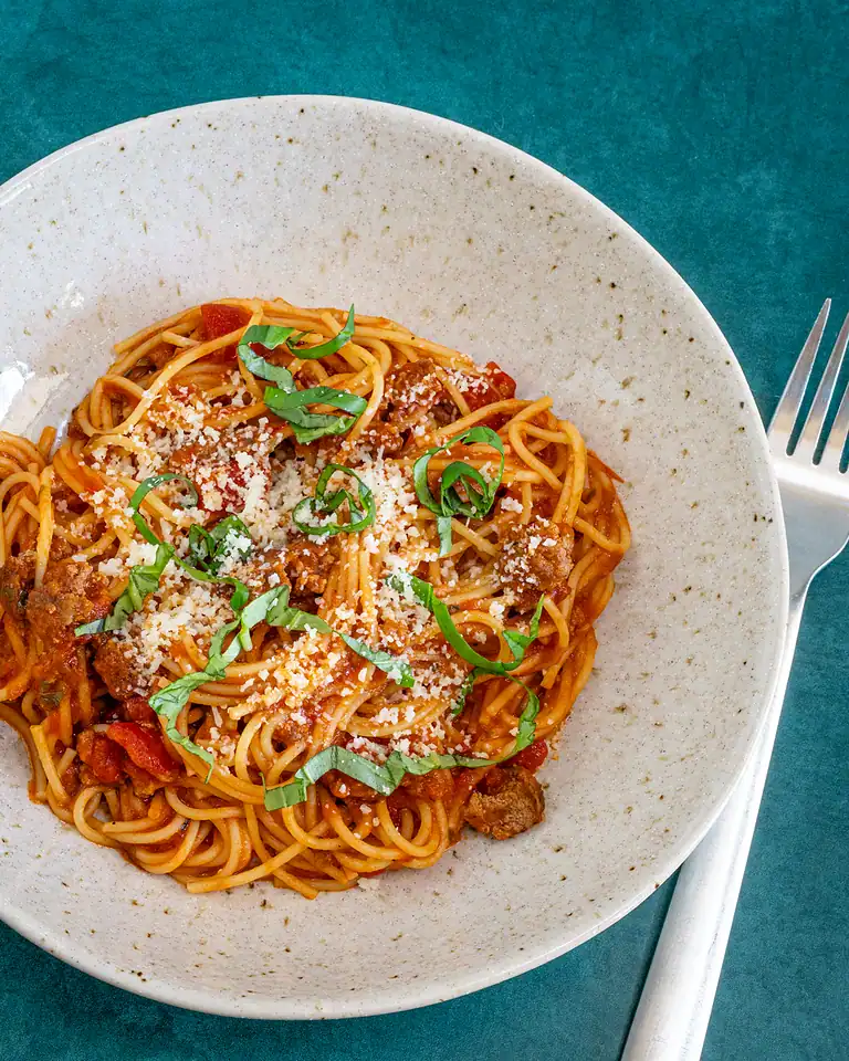 Savory spaghetti topped with fresh basil and grated cheese.