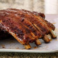 A rack of oven barbecued pork ribs on a plate.