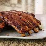 Succulent grilled pork ribs with a rich barbecue glaze on a white plate.