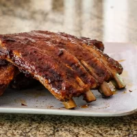 Succulent grilled pork ribs with a rich barbecue glaze on a white plate.