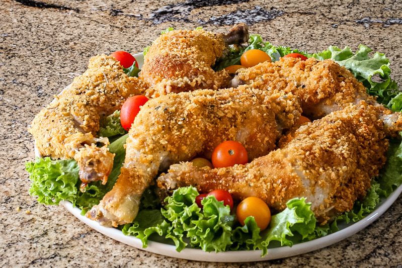 Closeup photo of cornflake crusted chicken on lettuce with some tomatoes scattered around the platter.
