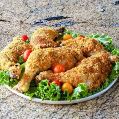 Cornflake crusted chicken on a platter with tomatoes and lettuce.