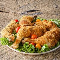 Oven fried cornflake coated chicken pieces on a platter.