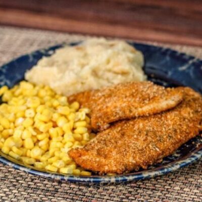 spiced oven fried chicken on a plate with potatoes and corn