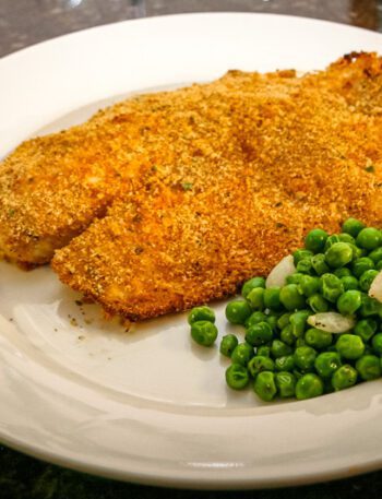 A plate with oven-fried tilapia and peas.
