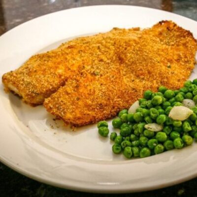 A plate with oven-fried tilapia and peas.