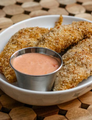bacon and panko coated chicken tenders on a plate with dip