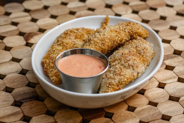 bacon and panko coated chicken tenders on a plate with dip