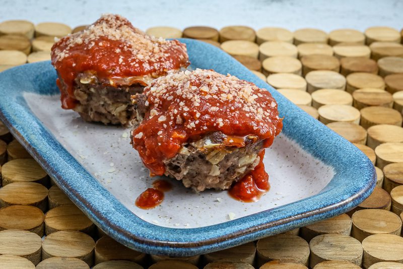 parmesan meatloaf in muffin shapes, topped with pizza sauce and extra parmesan cheese