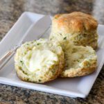 parsley biscuits on a plate, with one split with butter