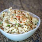 Pasta salad in a bowl with cucumbers and ham.