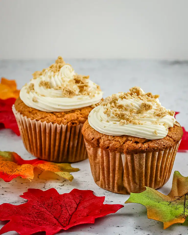 Freshly baked pumpkin cupcakes with creamy frosting and crumbled topping.
