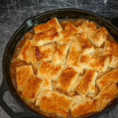 Crispy fried bread pieces soaking in sauce in a cast iron skillet.