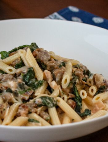 Creamy penne with sausage and spinach in a bowl