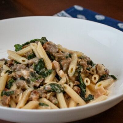 Creamy penne with sausage and spinach in a bowl