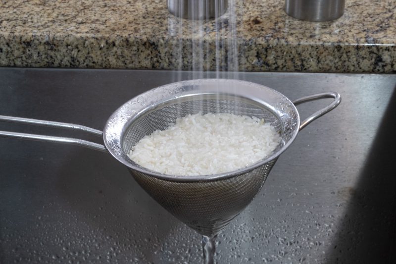 rinsing rice grains in a strainer