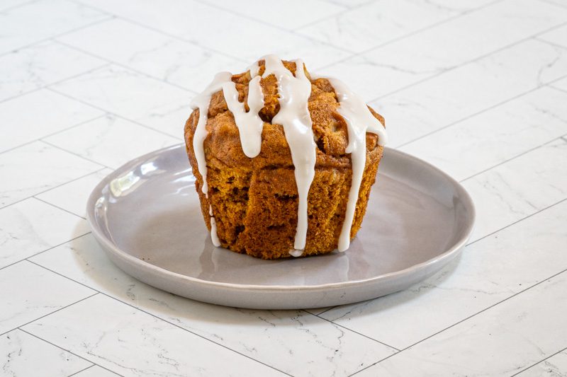 A pumpkin muffin with drizzle of vanilla glaze