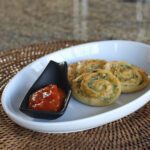 pesto pinwheel snack on a plate with marinara sauce