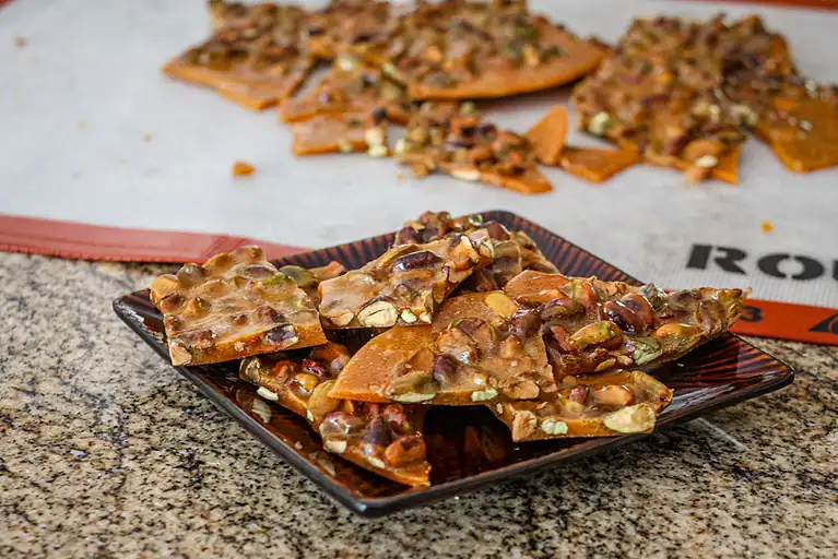 Homemade peanut butter brittle with mixed nuts and caramel droplets.