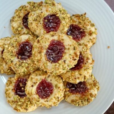 pistachio thumbprint cookies with jam center, arranged on a plate
