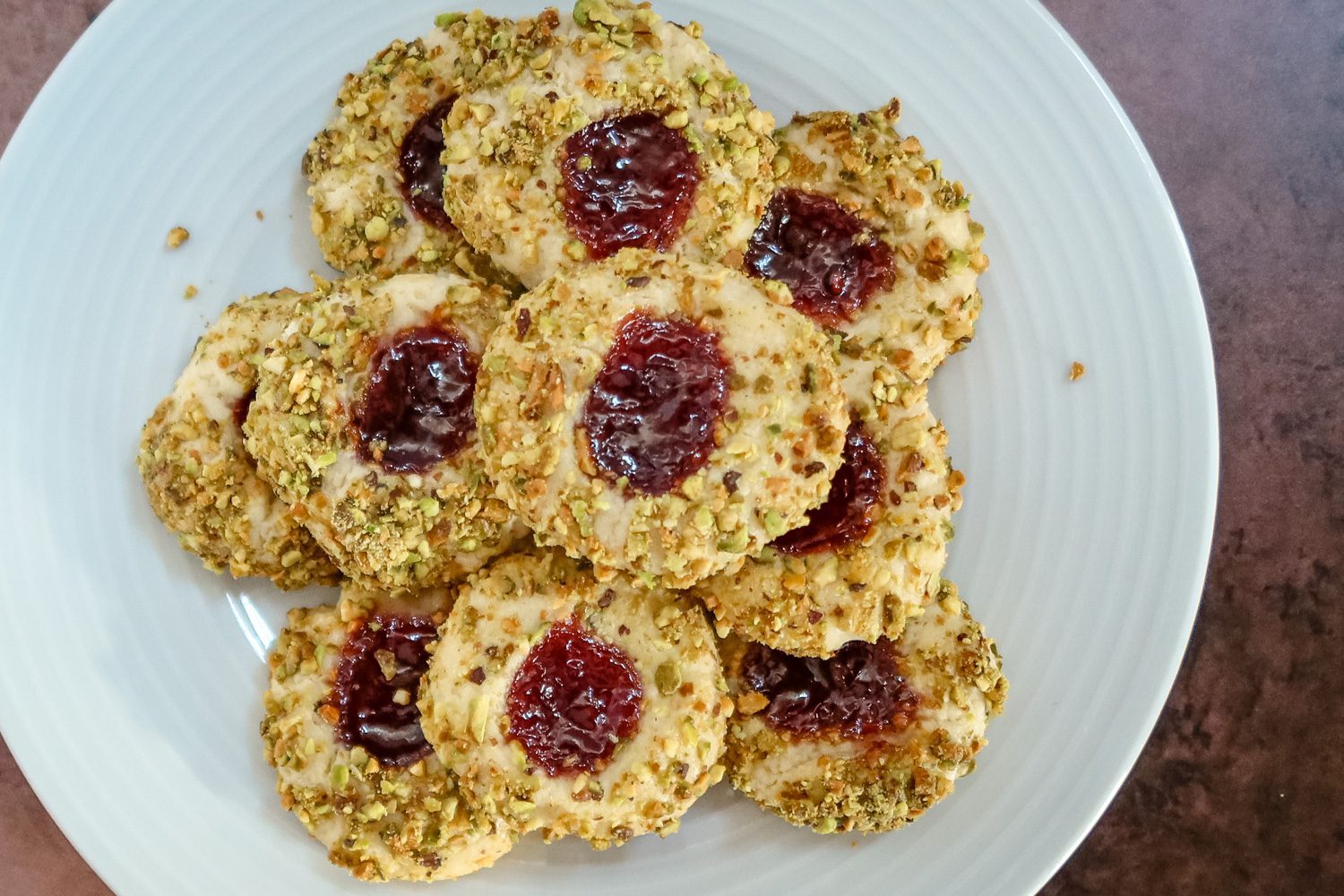 pistachio thumbprint cookies with jam center, arranged on a plate