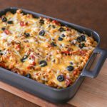 pizza casserole in the baking dish with cheese and olives