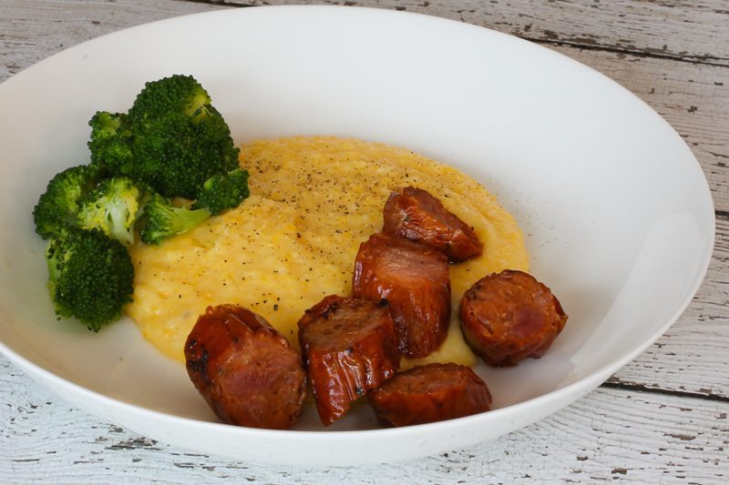 spicy andouille sausage and polenta in a bowl with broccoli on the side