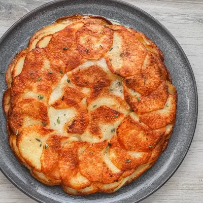 Golden baked potato gratin in a black dish.