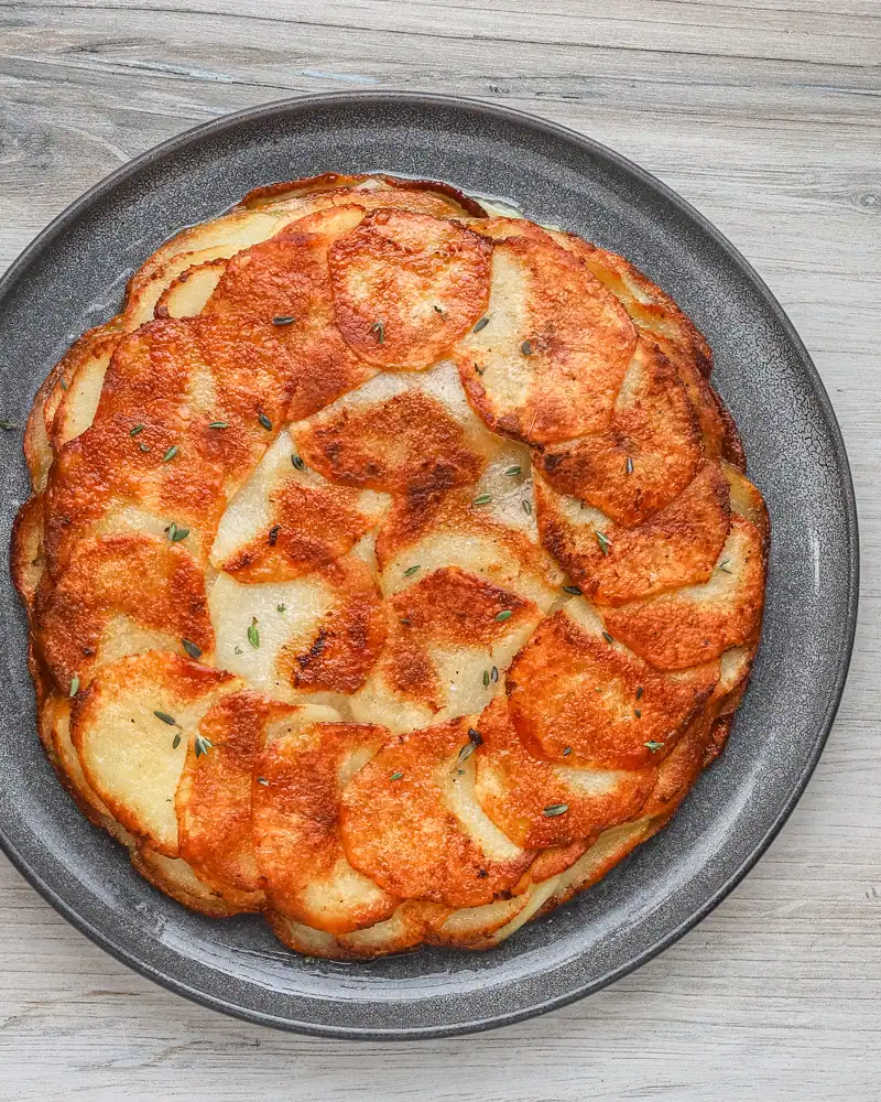 Golden baked potato gratin in a black dish.