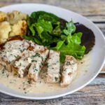 boneless pork chops are served on a plate with a mustard cream sauce and cauliflower.