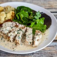 boneless pork chops are served on a plate with a mustard cream sauce and cauliflower.