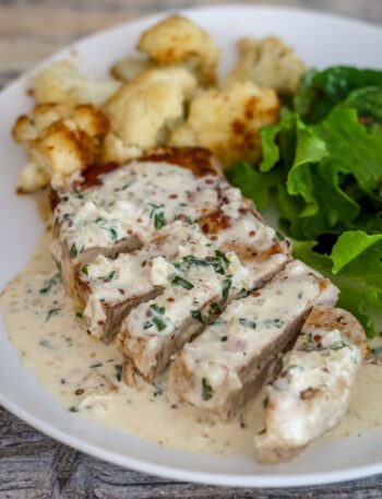 pork chops with mustard cream sauce on a plate with cauliflower and salad